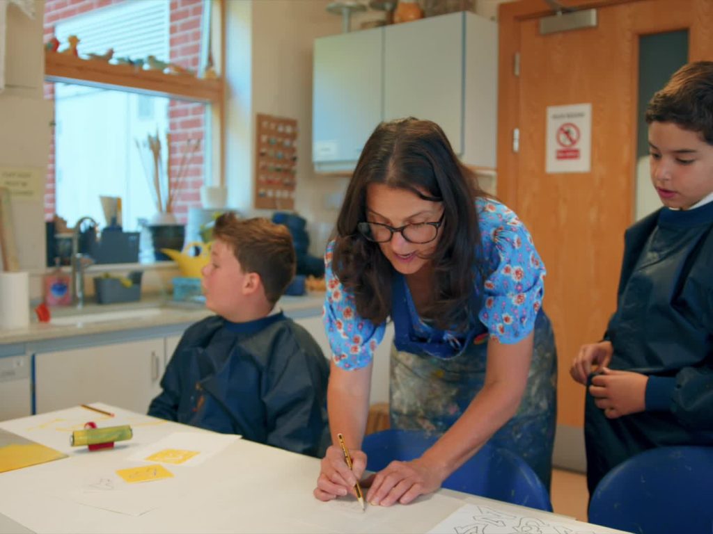 teacher helping pupils with their artwork