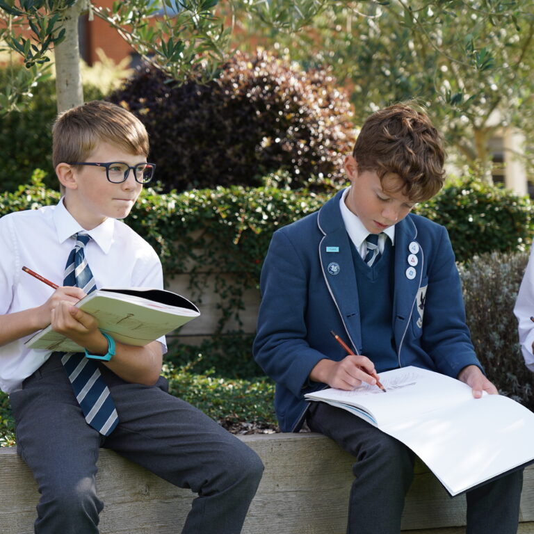 3 boys drawing into booklets