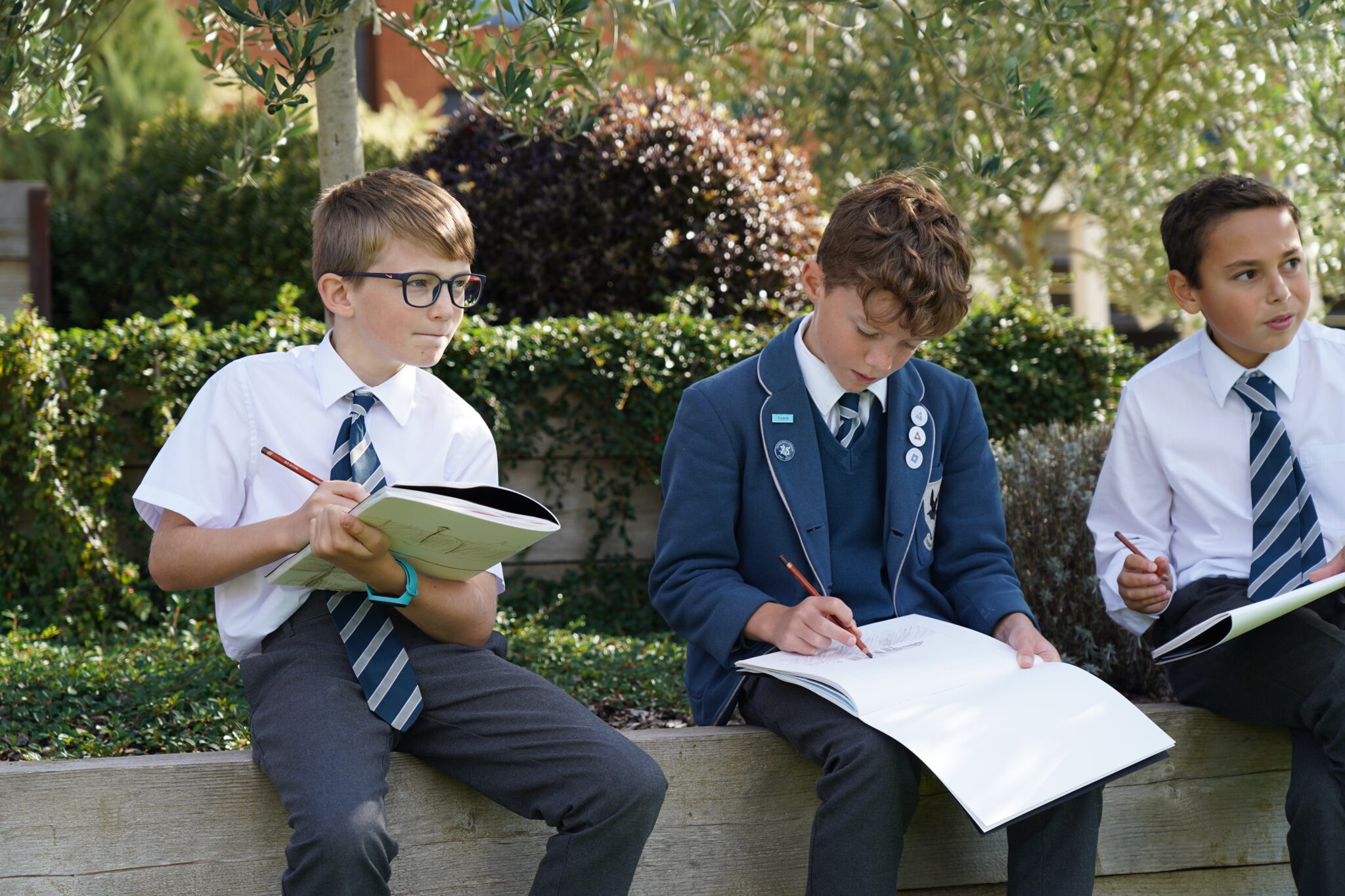 3 boys drawing into booklets